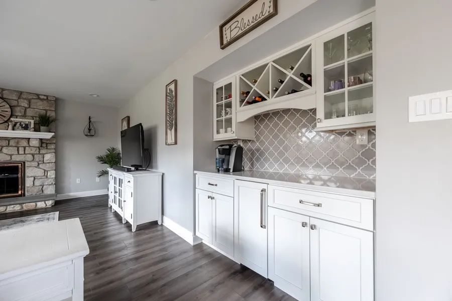 A kitchen with white cabinets and a wine rack.