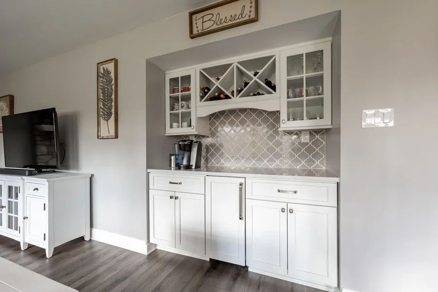 A kitchen with white cabinets and a wine rack.