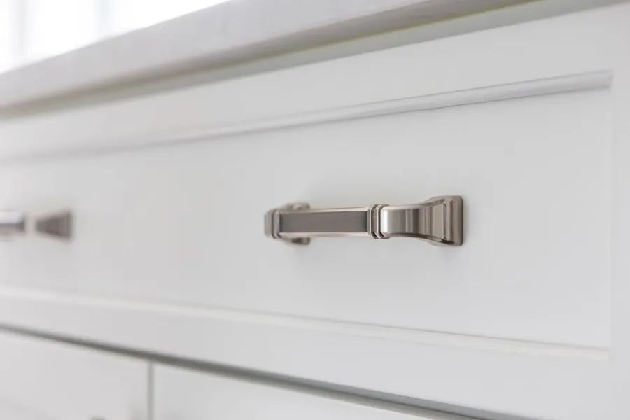 A close up of a white cabinet with a bow handle.