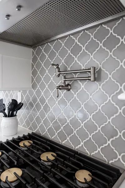 A kitchen with a stove top oven and a faucet on the wall.