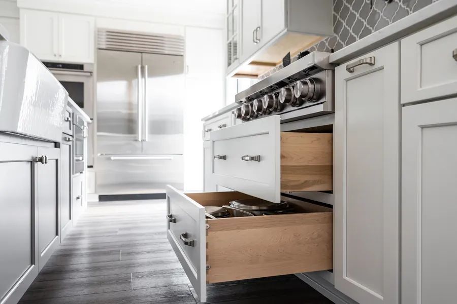 A kitchen with white cabinets , stainless steel appliances , and wooden drawers.