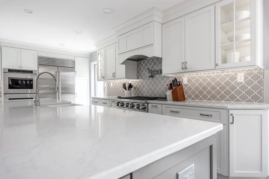 A kitchen with white cabinets , white counter tops , and stainless steel appliances.