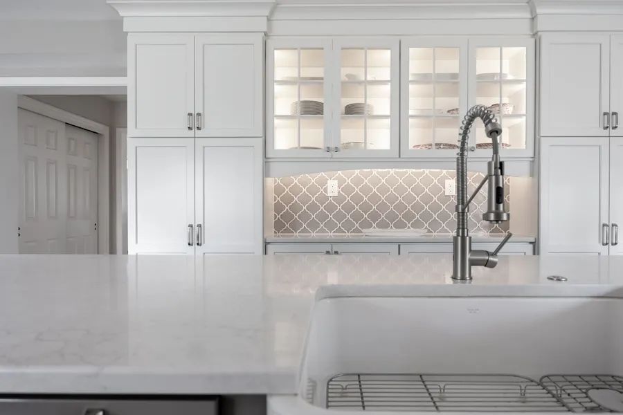 A kitchen with white cabinets , a sink , and a faucet.