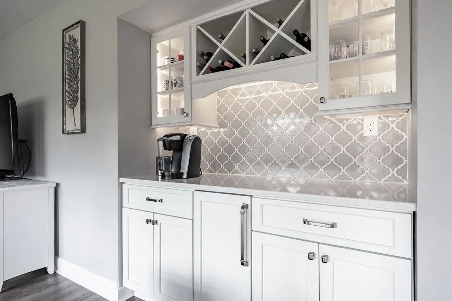 A kitchen with white cabinets and a wine rack.