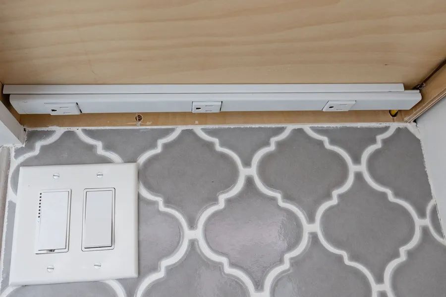 A light switch is sitting on a rug under a table.