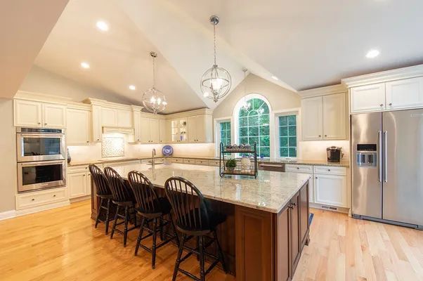 A kitchen with white cabinets , stainless steel appliances , granite counter tops , and a large island.