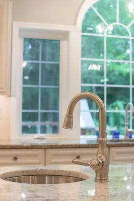 A kitchen sink with a faucet and a window in the background.