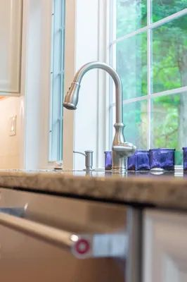 A kitchen sink with a faucet and a window in the background.