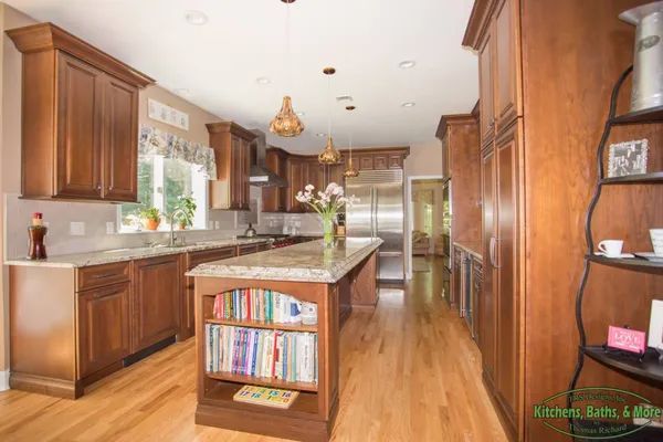 A kitchen with wooden cabinets , stainless steel appliances , and a large island.