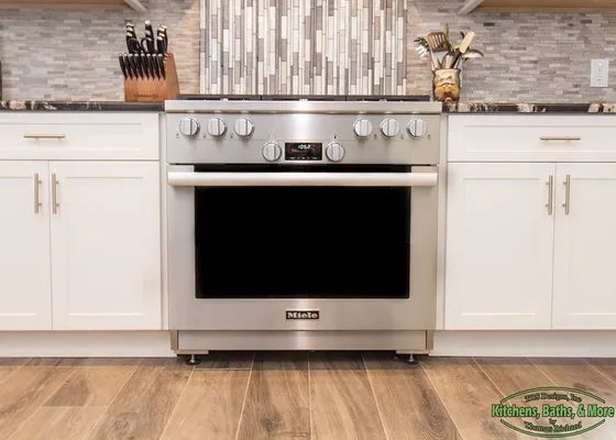 A stainless steel stove in a kitchen with white cabinets.