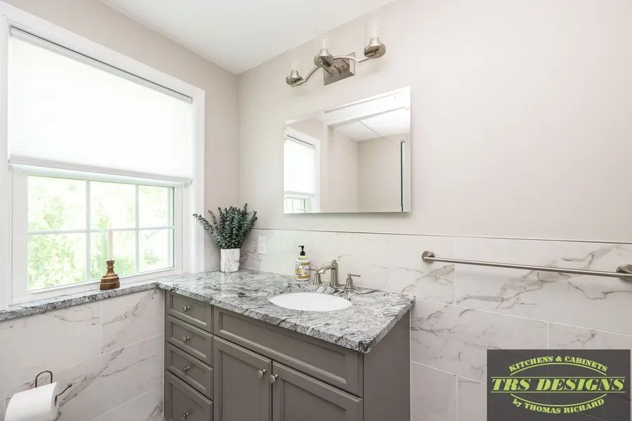 A bathroom with a sink, mirror and window.