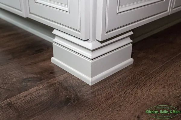 A white cabinet with a wooden floor underneath it.