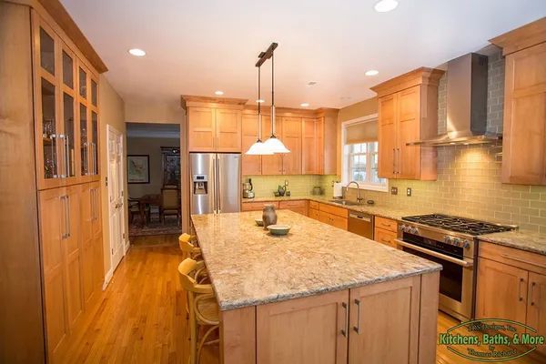 A kitchen with wooden cabinets, granite counter tops, stainless steel appliances and a large island.