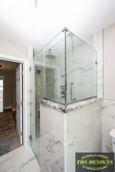 A bathroom with a walk in shower with a glass door.
