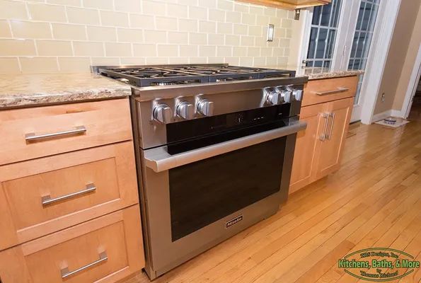 A stove and oven in a kitchen with wooden cabinets.