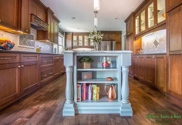 A kitchen with wooden cabinets and a large island in the middle.
