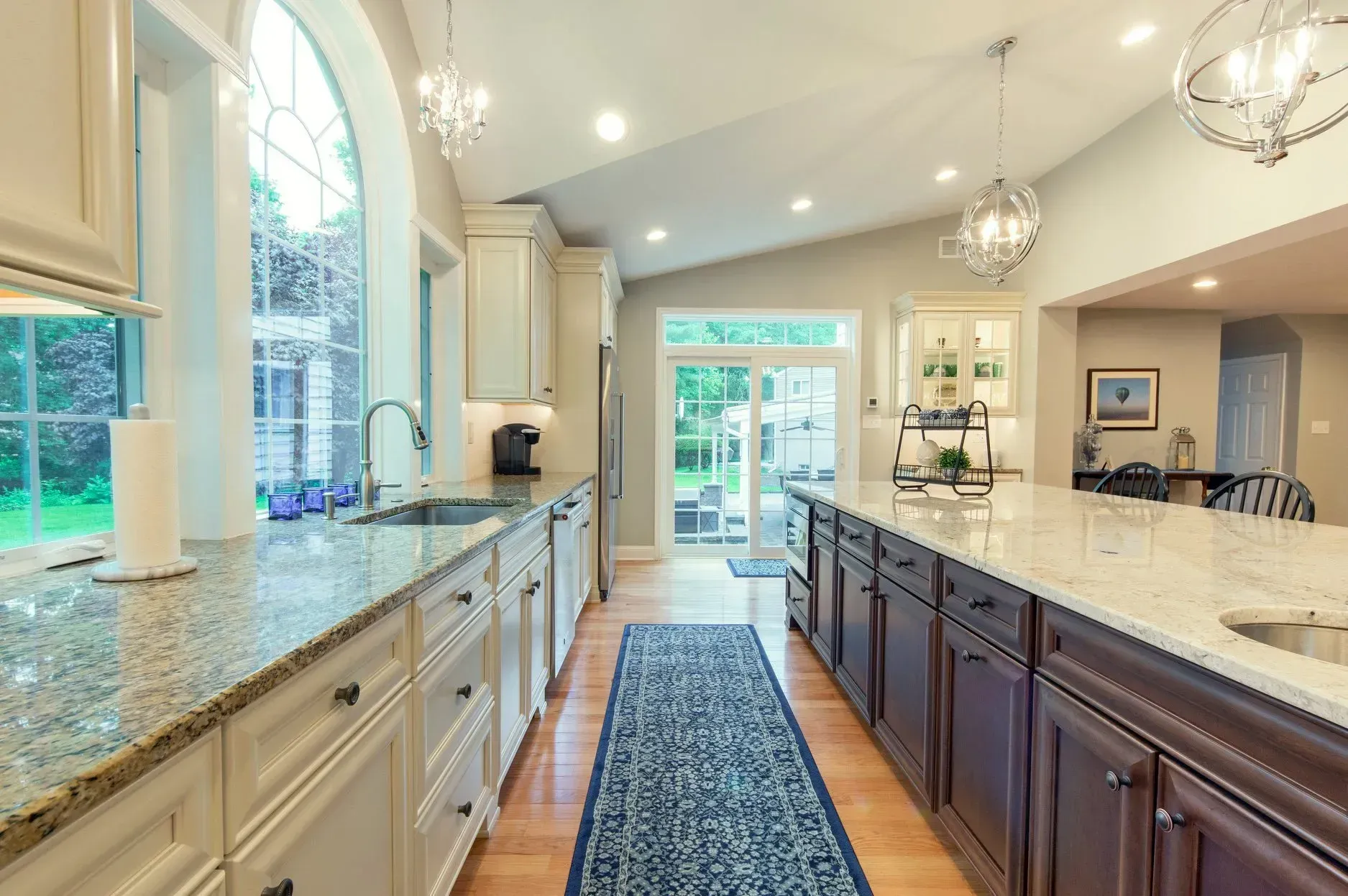 A kitchen with granite counter tops, purple cabinets, and a blue rug.