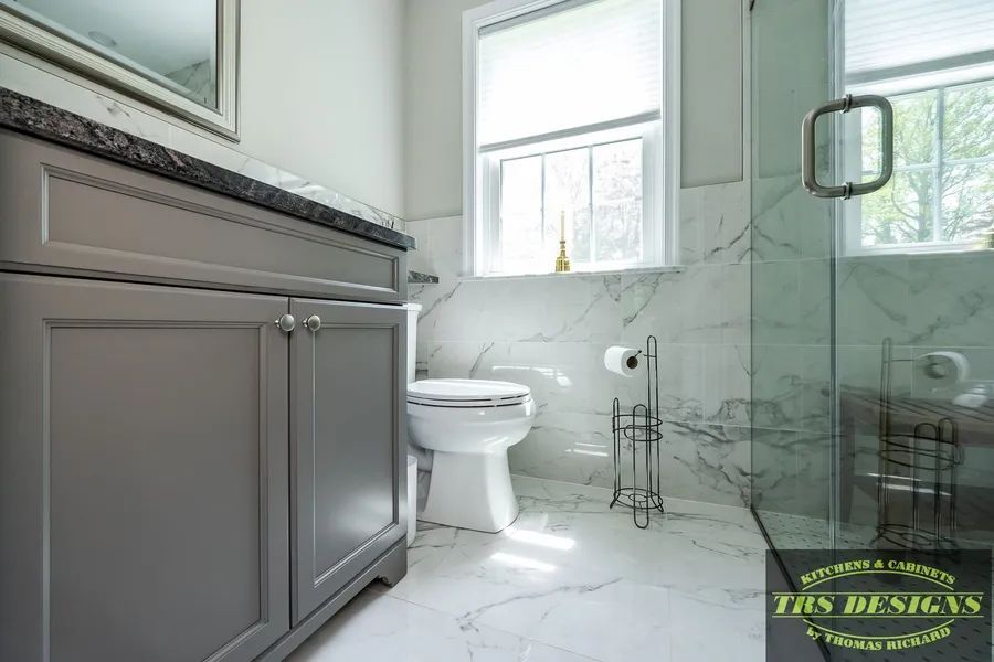 A bathroom with a toilet, sink, mirror and walk in shower.