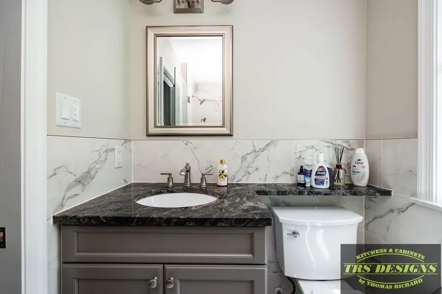 A bathroom with a sink, toilet and mirror.