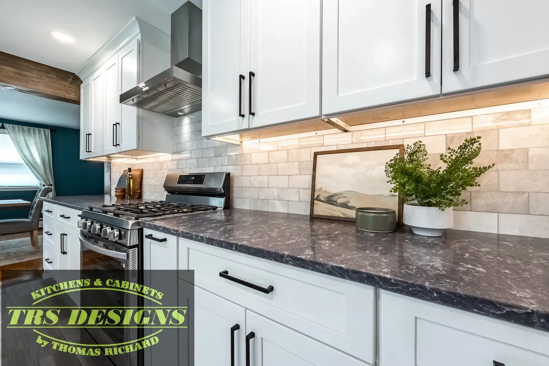 A kitchen with white cabinets and black granite counter tops.