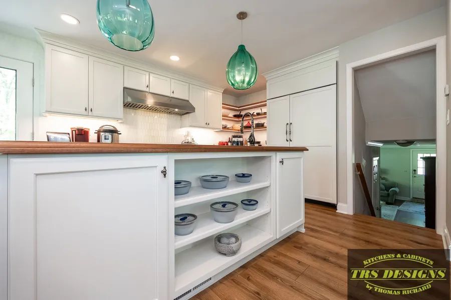 A kitchen with white cabinets and a wooden counter top.