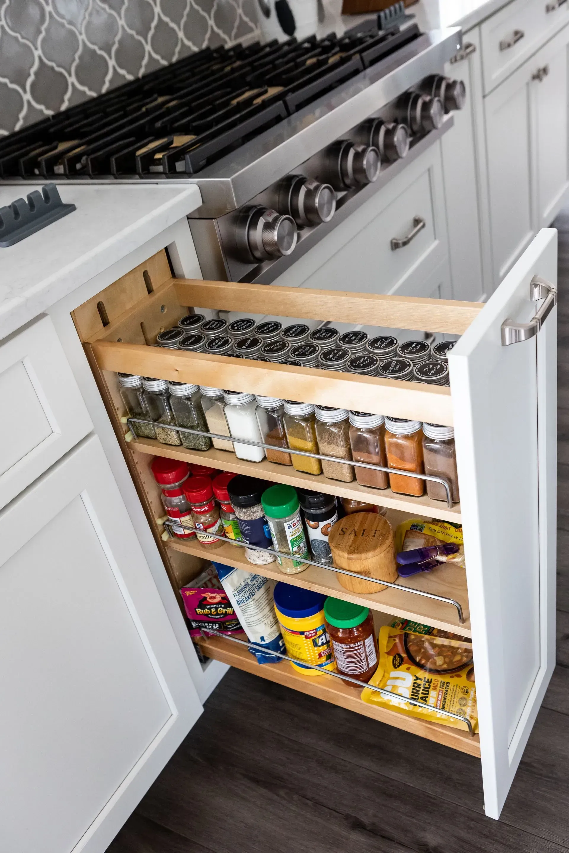 A kitchen with a pull out spice rack and a stove.
