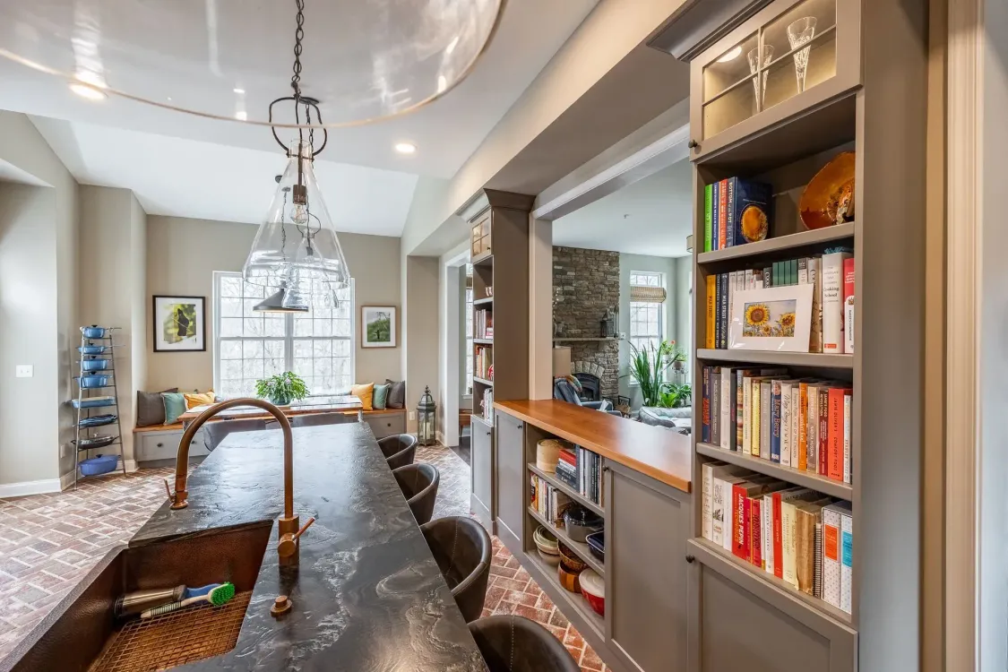 A kitchen with a large island, sink, and bookshelf.