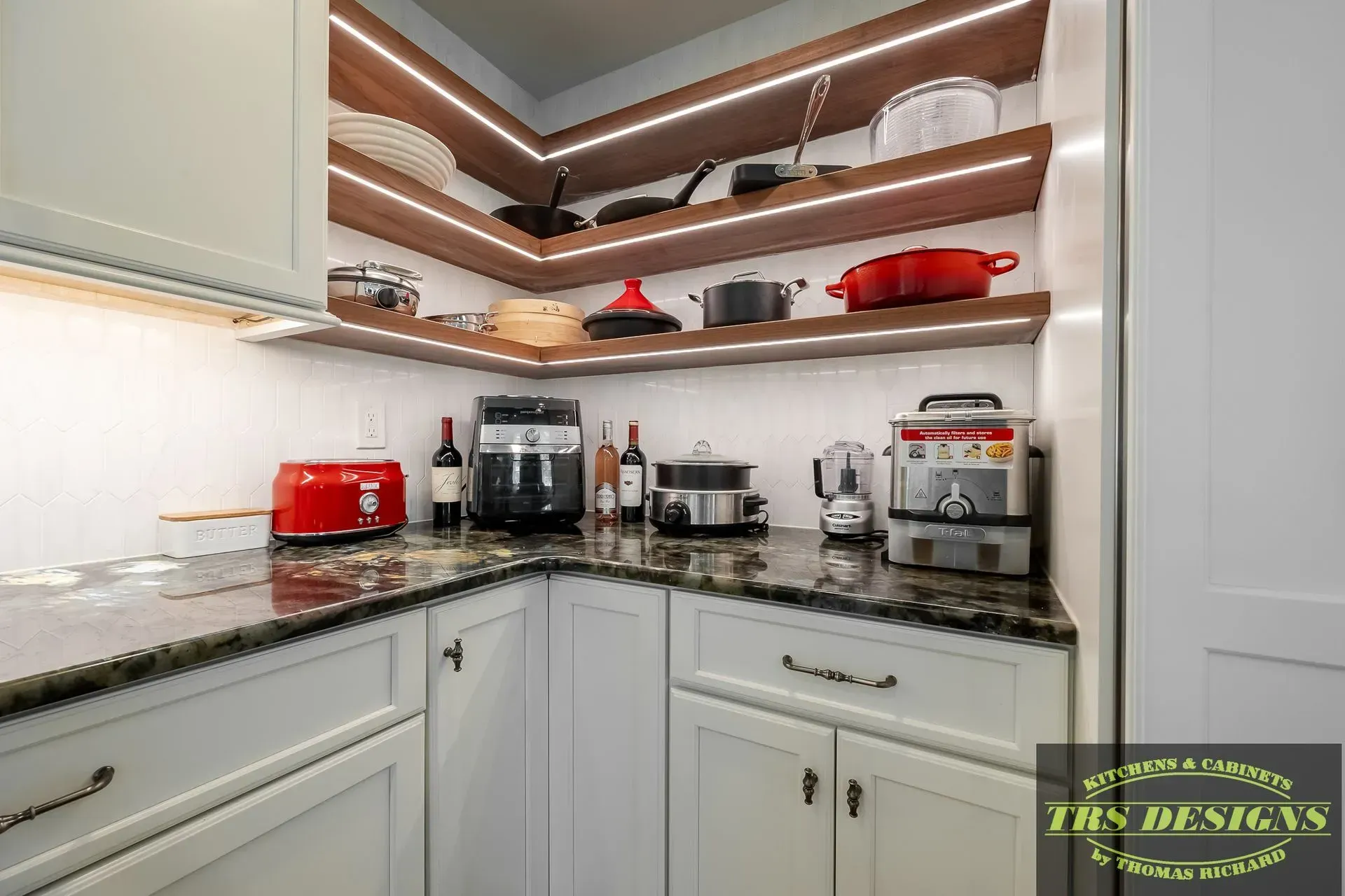 A kitchen with white cabinets, granite counter tops, and wooden shelves.