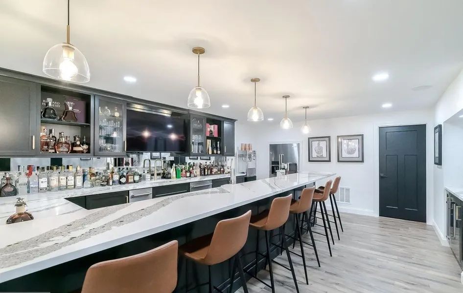 A long bar with stools and bottles of liquor on it.