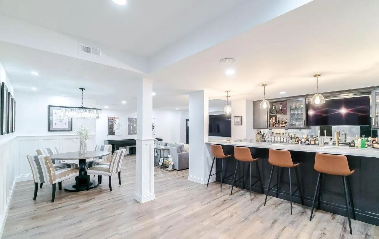 A basement with a table and chairs and a bar.