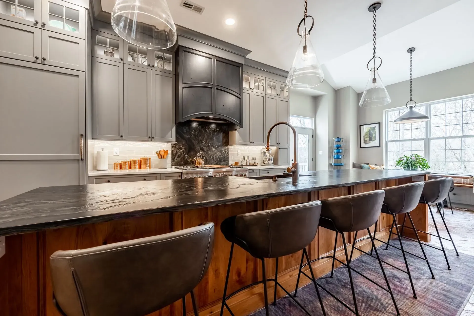 A kitchen with a long island and a lot of chairs.