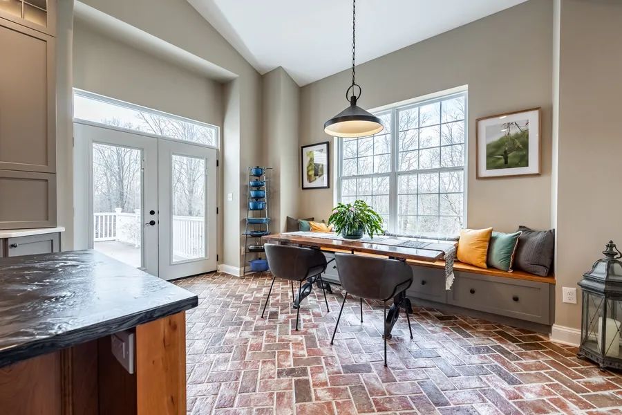 A dining room with a table and chairs and a window seat.