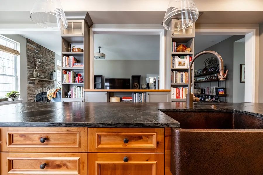 A kitchen with a copper sink and a black counter top.