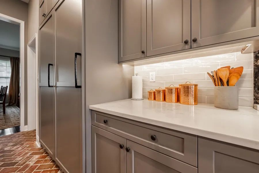 A kitchen with gray cabinets and stainless steel appliances.