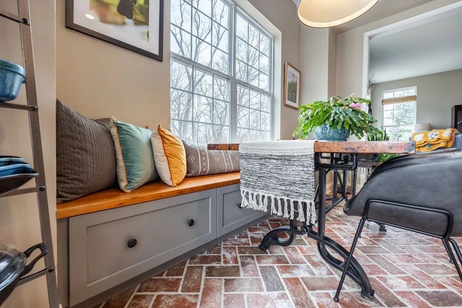 A dining room with a bench and a table in front of a window.