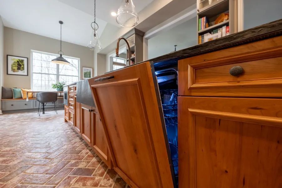 A kitchen with wooden cabinets and a dishwasher with the door open.