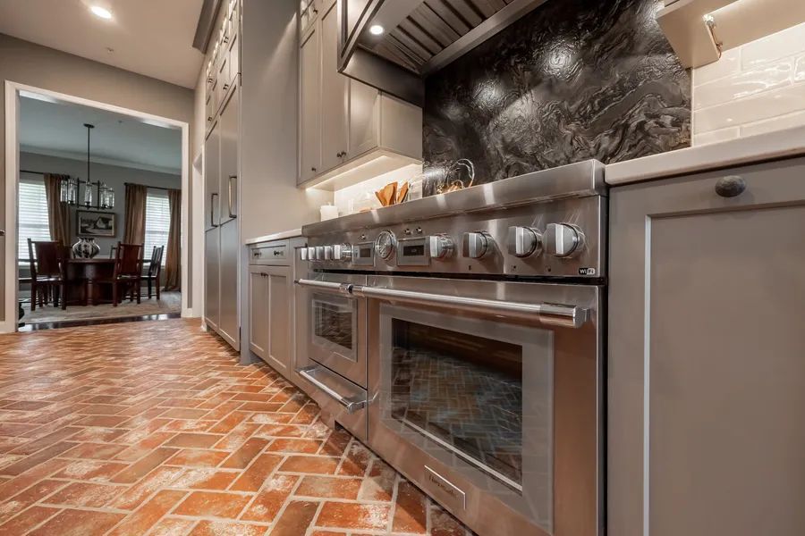 A kitchen with stainless steel appliances and a brick floor.
