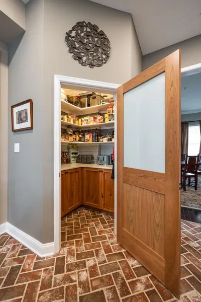 A pantry with a brick floor and a wooden door