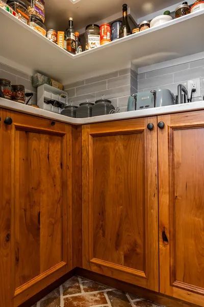 A kitchen with wooden cabinets and shelves filled with food.