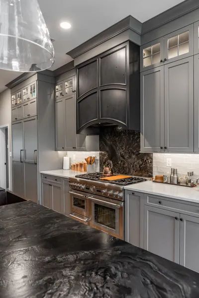 A kitchen with gray cabinets and a black counter top.