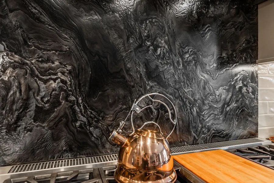 A copper tea kettle is sitting on top of a stove in a kitchen.