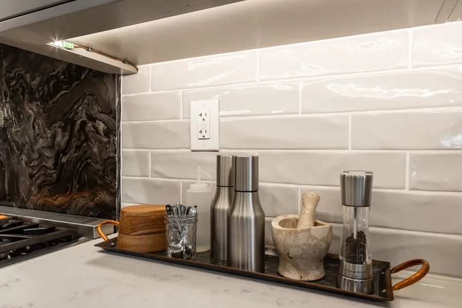 A kitchen counter with a tray of salt and pepper shakers and a mortar and pestle.