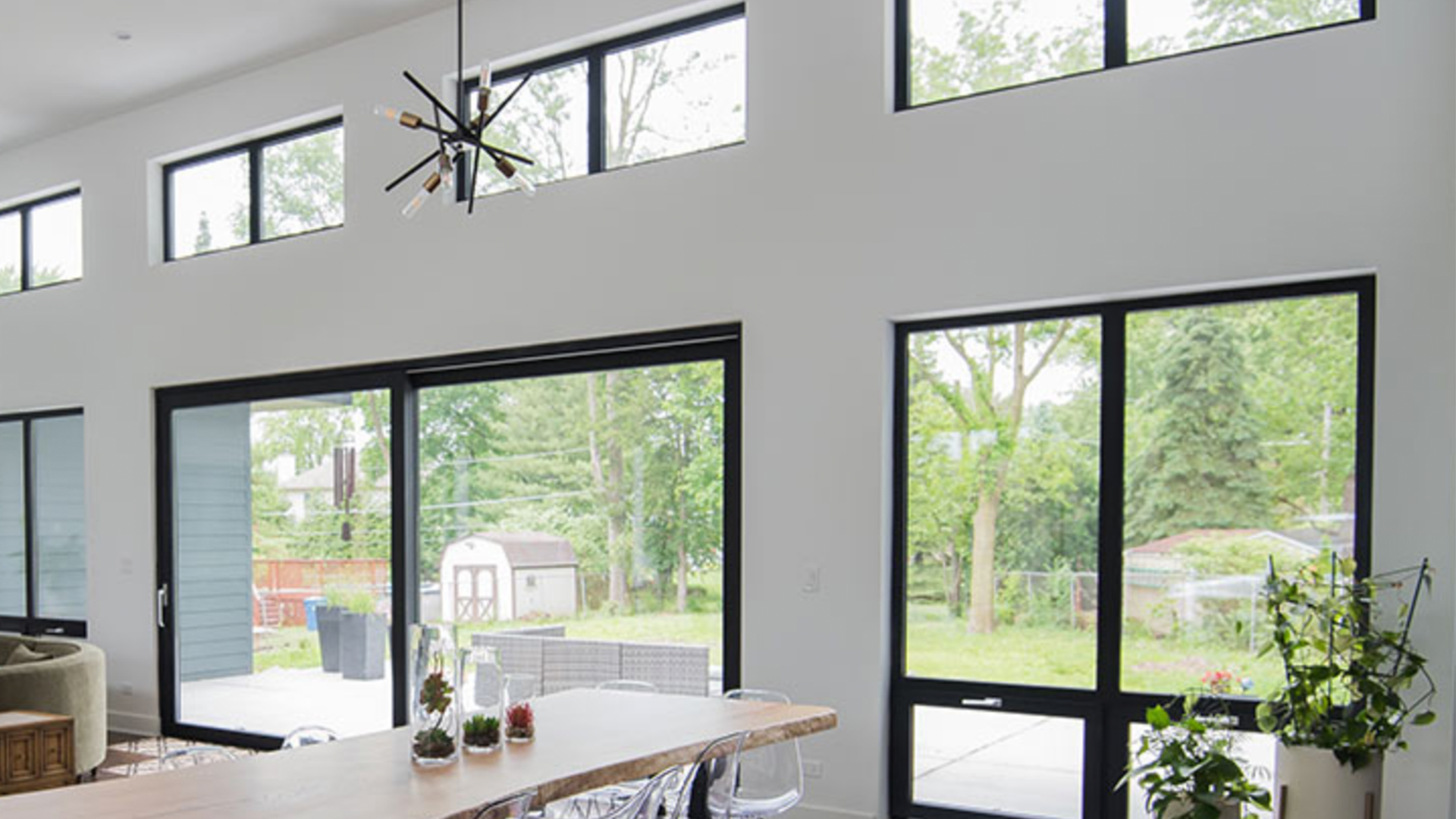 A dining room with a table and chairs and a lot of windows.