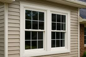 “Energy-efficient double-hung replacement windows with white frames installed on a beige-sided home.