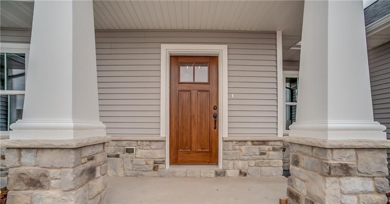 Front porch entrance with a wooden door and stone pillars.