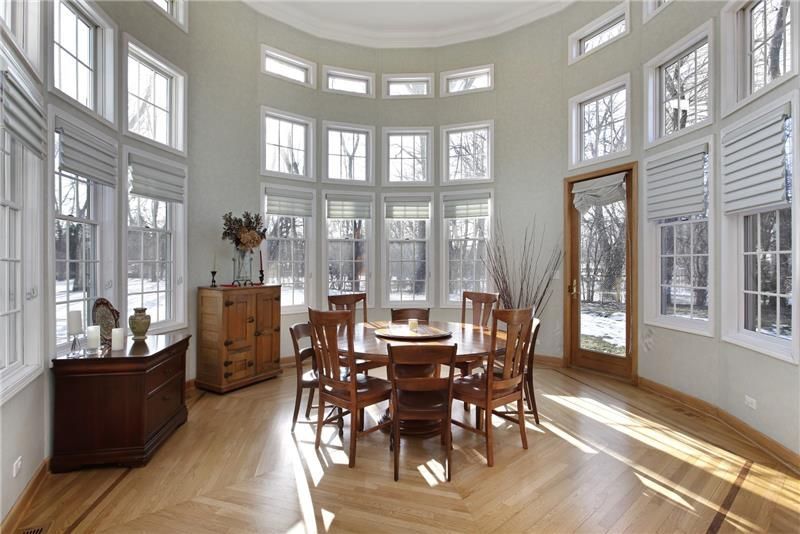Bright dining area with large windows and a round wooden table.