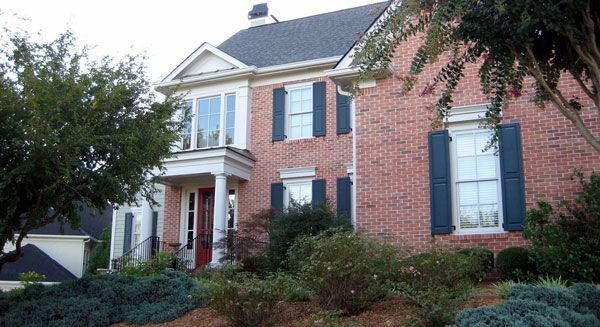 A large red brick house with blue shutters on the windows