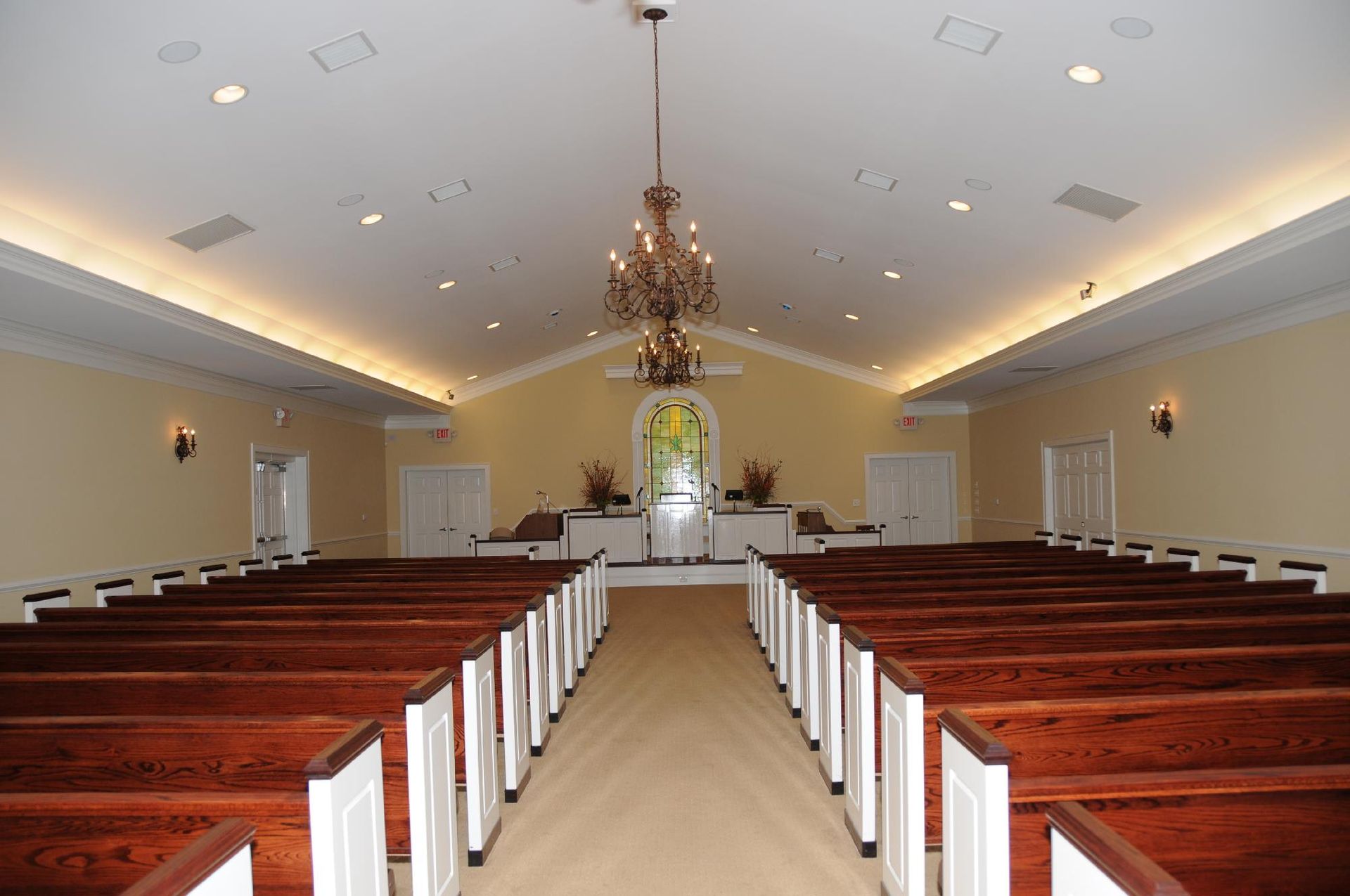A church with rows of wooden pews and a chandelier hanging from the ceiling