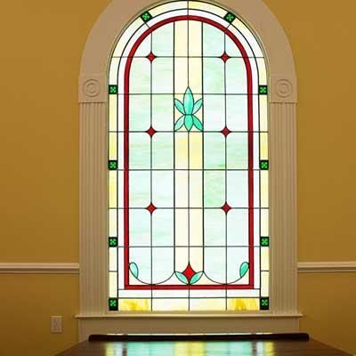 A stained glass window in a room with a table in front of it.