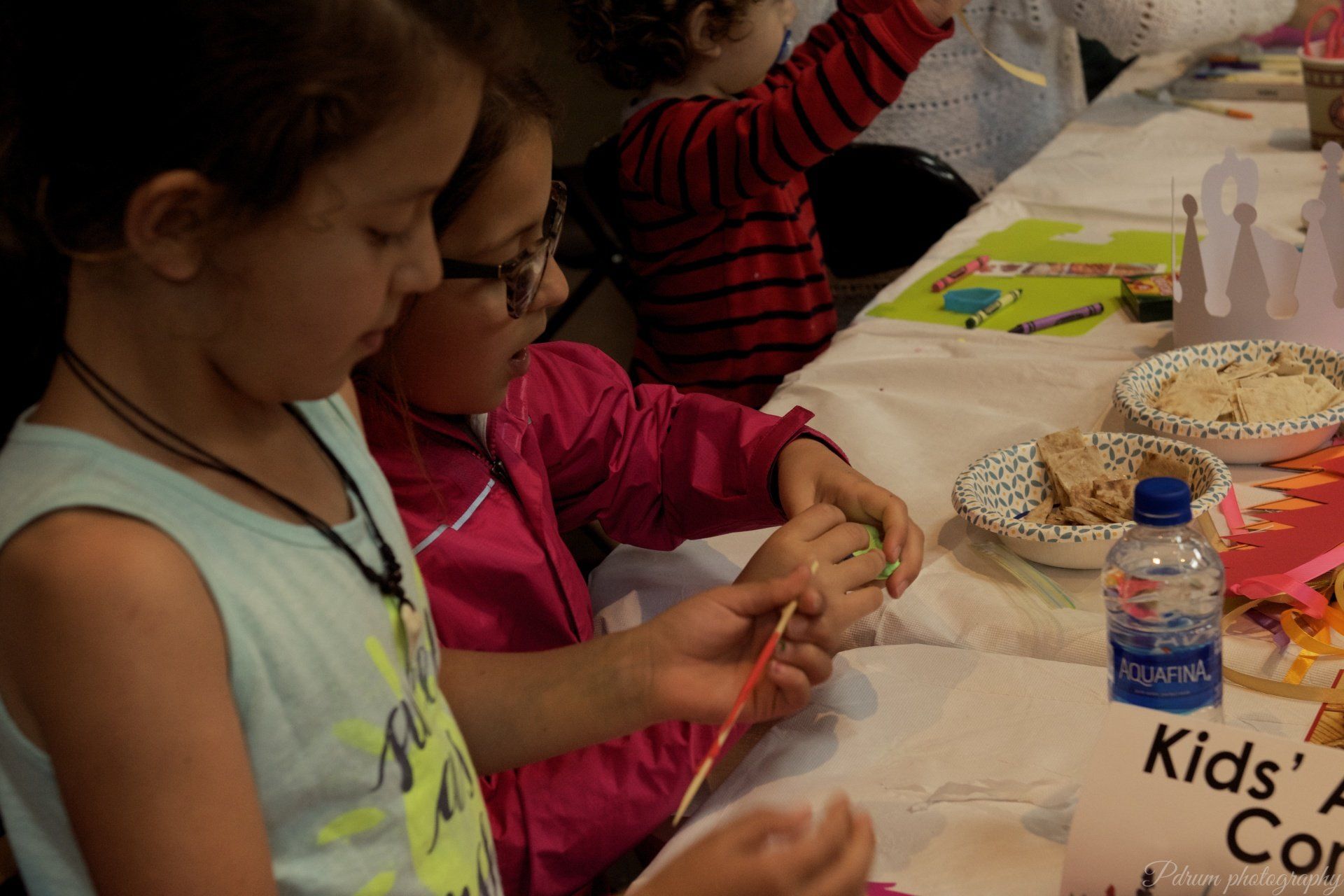 A group of children are sitting at a table with a sign that says kids ' corner